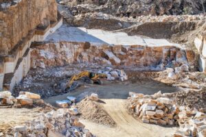 Open-pit stone quarry with excavator showing the scale and complexity of mining sites surveyed by UAV drones